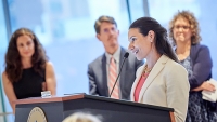 CPTR trainee speaks at ceremony while faculty members look on.
